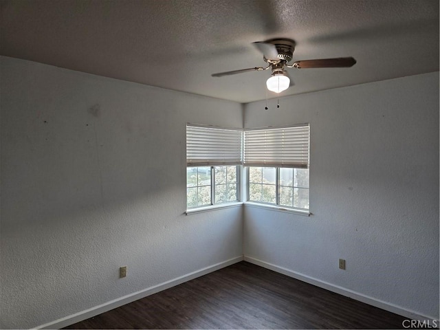 unfurnished room with ceiling fan, baseboards, dark wood-type flooring, and a textured ceiling