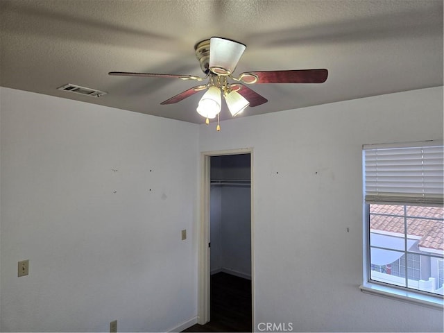 unfurnished bedroom featuring a textured ceiling, a closet, ceiling fan, baseboards, and visible vents