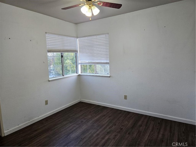 spare room with a ceiling fan, baseboards, and dark wood-style flooring