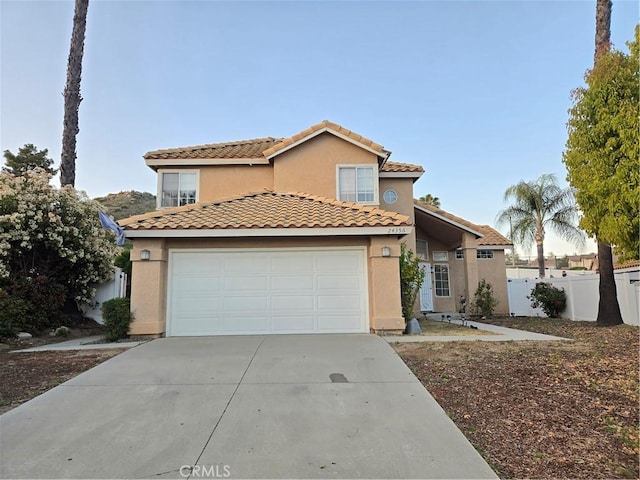 view of front of home with stucco siding, fence, concrete driveway, and a tiled roof