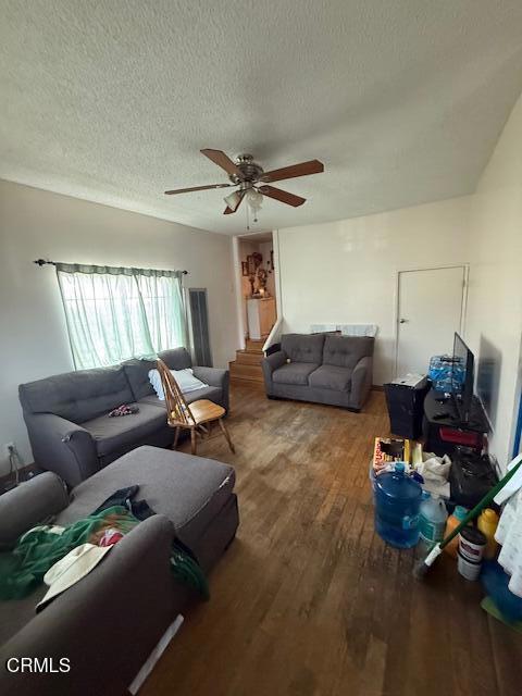 living room with a textured ceiling, ceiling fan, and wood finished floors
