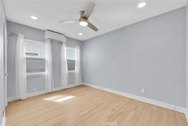 unfurnished room with baseboards, an AC wall unit, recessed lighting, a ceiling fan, and wood finished floors