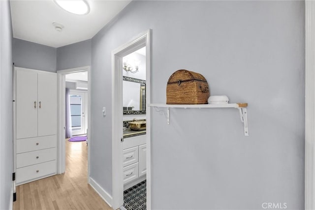 hallway featuring light wood finished floors and baseboards