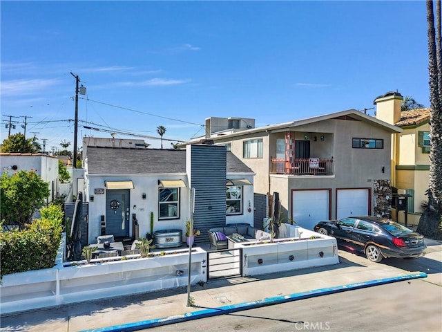townhome / multi-family property with concrete driveway, a chimney, a garage, and stucco siding