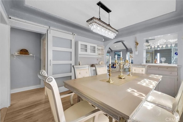 dining space with baseboards, arched walkways, and light wood-style floors