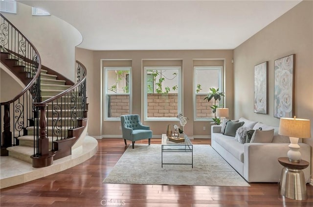 living area with baseboards, wood finished floors, and stairs