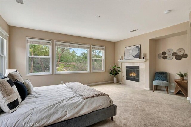 bedroom featuring baseboards, a tile fireplace, visible vents, and carpet floors