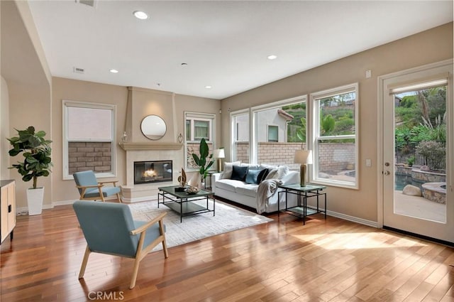 living room with hardwood / wood-style floors, baseboards, a large fireplace, and visible vents