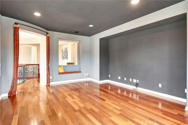 unfurnished room with visible vents, wood finished floors, baseboards, and recessed lighting