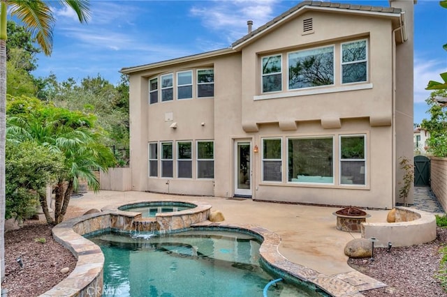 rear view of house featuring an in ground hot tub, a patio, an outdoor fire pit, an outdoor pool, and stucco siding