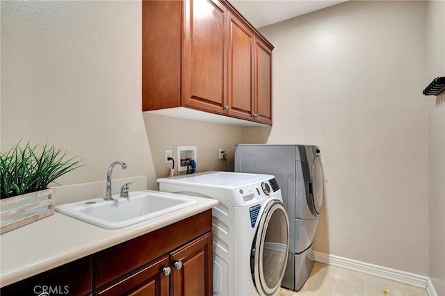 clothes washing area featuring a sink, washing machine and dryer, baseboards, cabinet space, and light tile patterned floors