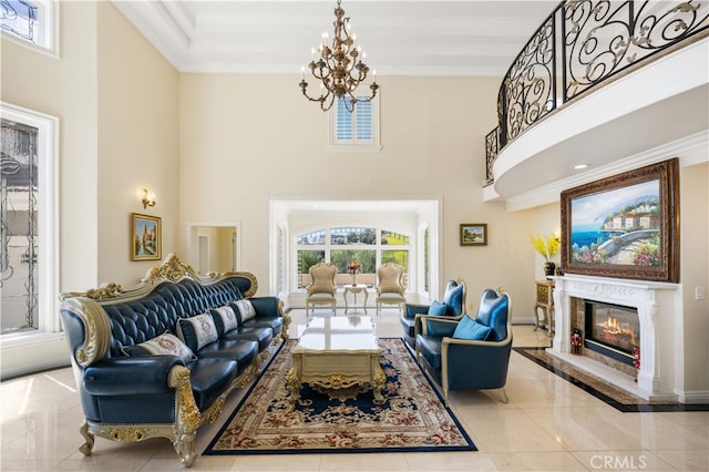 living area featuring a towering ceiling, a chandelier, a fireplace, ornamental molding, and baseboards