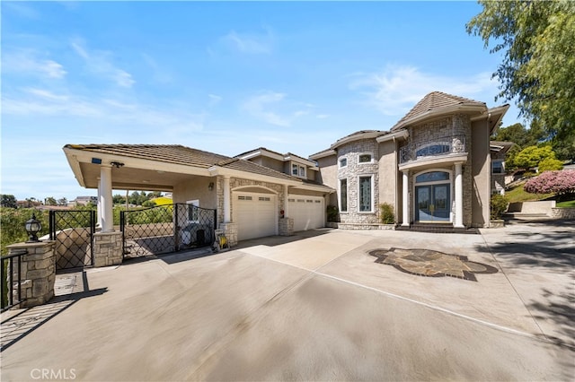 view of front of house featuring stone siding, french doors, an attached garage, a gate, and concrete driveway