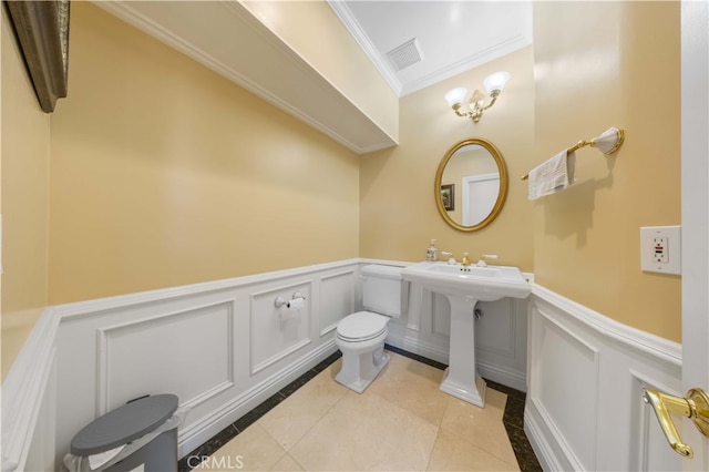 bathroom featuring ornamental molding, a wainscoted wall, a decorative wall, tile patterned flooring, and toilet