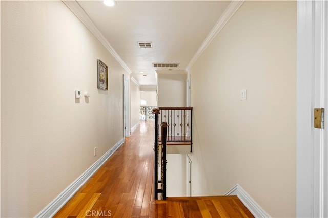 corridor with an upstairs landing, hardwood / wood-style flooring, crown molding, and baseboards