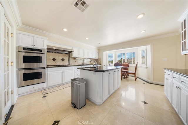 kitchen with appliances with stainless steel finishes, dark countertops, a sink, decorative backsplash, and ornamental molding
