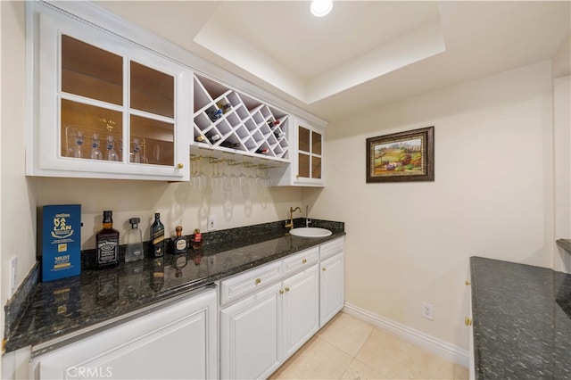indoor wet bar featuring light tile patterned floors, baseboards, and a tray ceiling