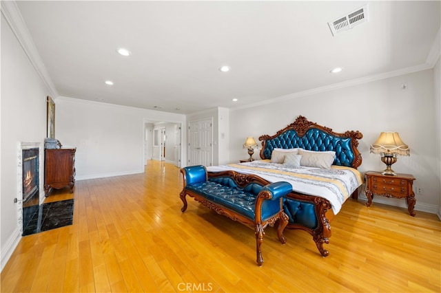 bedroom with light wood-type flooring, baseboards, ornamental molding, recessed lighting, and a high end fireplace