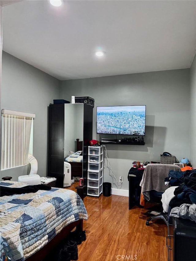 bedroom with wood finished floors, baseboards, and recessed lighting