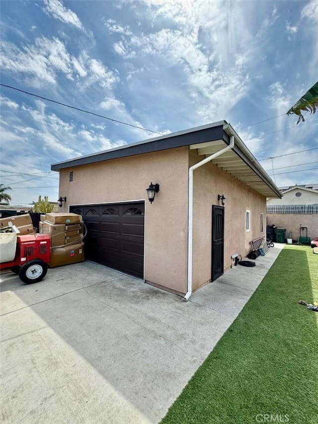 view of property exterior featuring driveway, fence, a lawn, and stucco siding