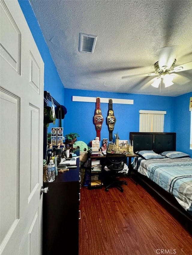 bedroom with visible vents, a ceiling fan, wood finished floors, and a textured ceiling
