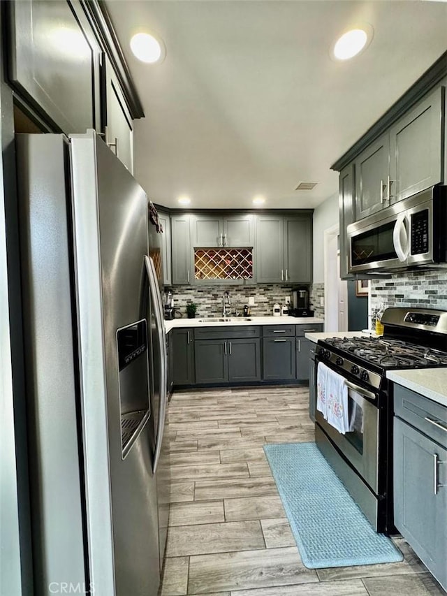 kitchen with a sink, backsplash, light countertops, and stainless steel appliances