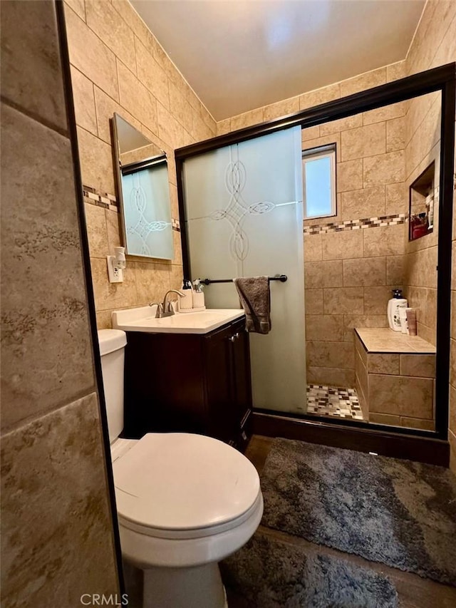 full bath with a shower stall, tile walls, vanity, and toilet