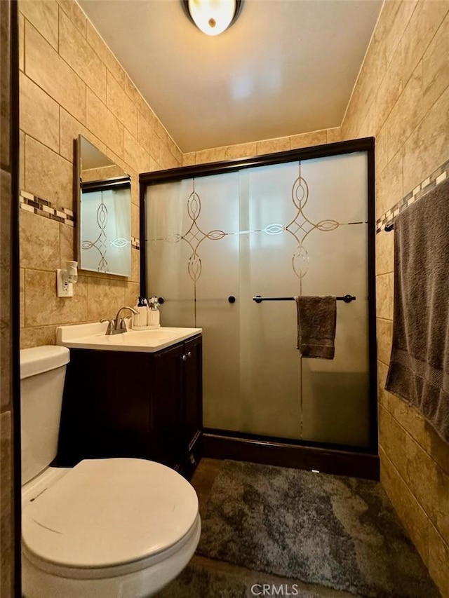 full bathroom with toilet, tile walls, a stall shower, and vanity