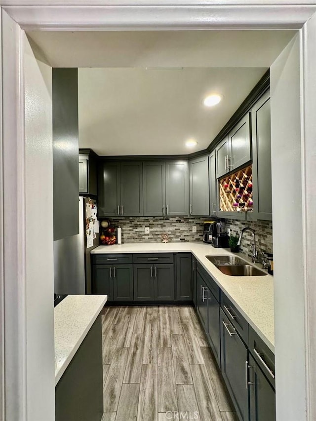 kitchen with freestanding refrigerator, light wood-style flooring, recessed lighting, a sink, and backsplash