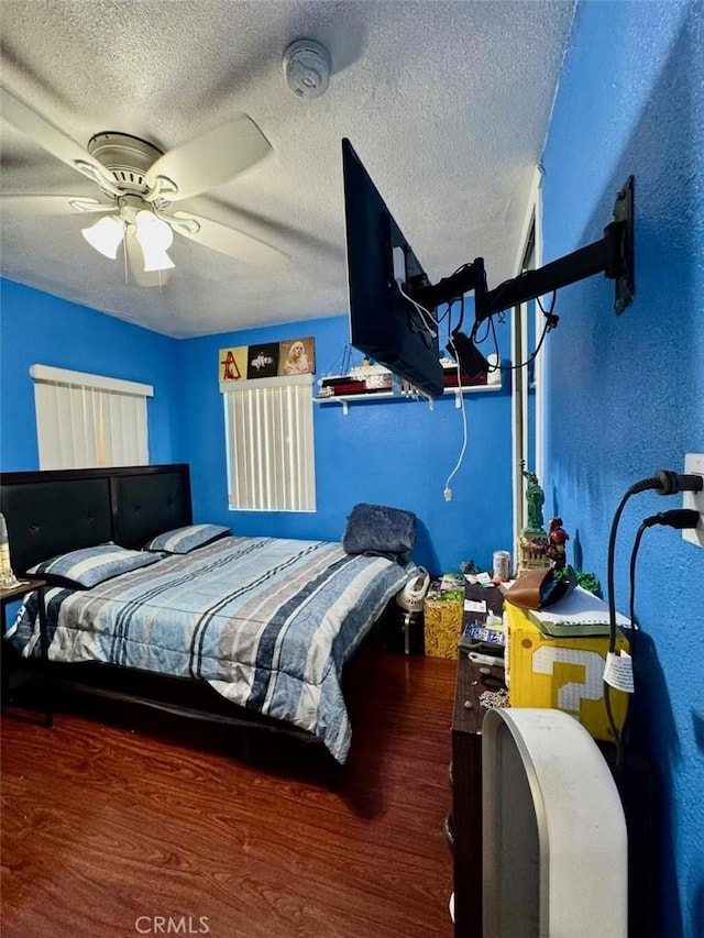bedroom with a ceiling fan, wood finished floors, and a textured ceiling