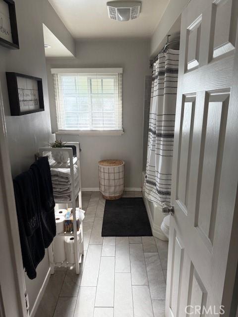 11406 Christy Ave, Sylmar, CA 91342 - bathroom with baseboards, tile patterned floors, and shower / tub combo with curtain