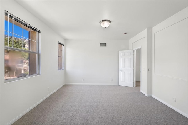 empty room featuring baseboards, visible vents, and carpet