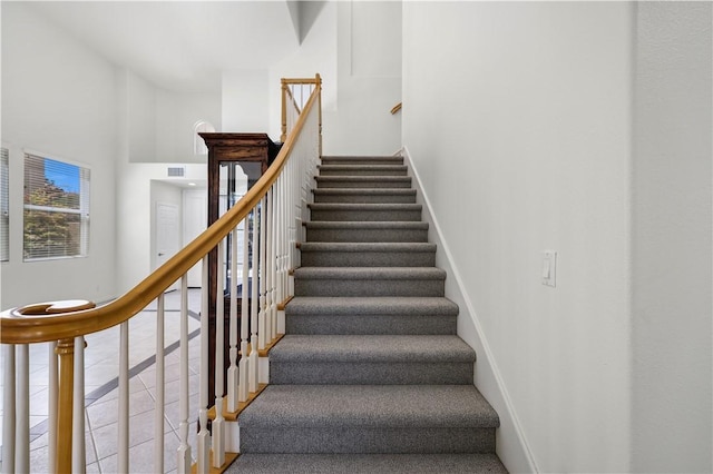 stairs featuring baseboards, visible vents, and a towering ceiling