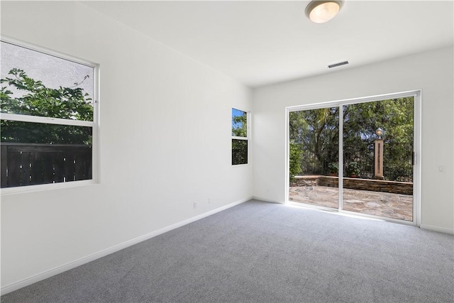 empty room featuring baseboards, visible vents, and carpet