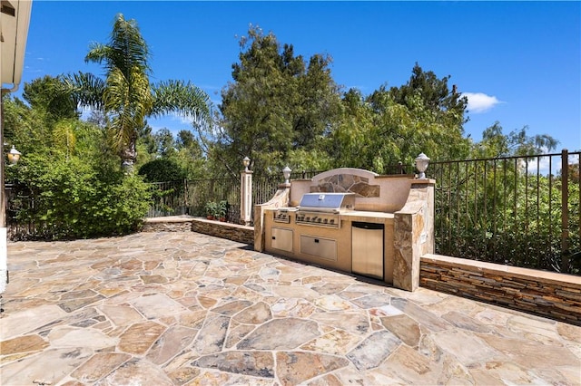 view of patio / terrace featuring fence, area for grilling, and an outdoor kitchen