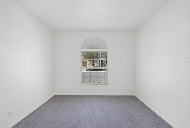 carpeted spare room featuring baseboards