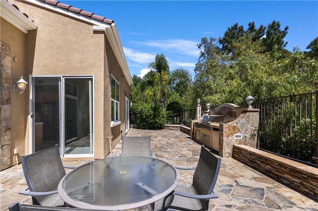 view of patio with grilling area, outdoor dining area, a fenced backyard, and exterior kitchen