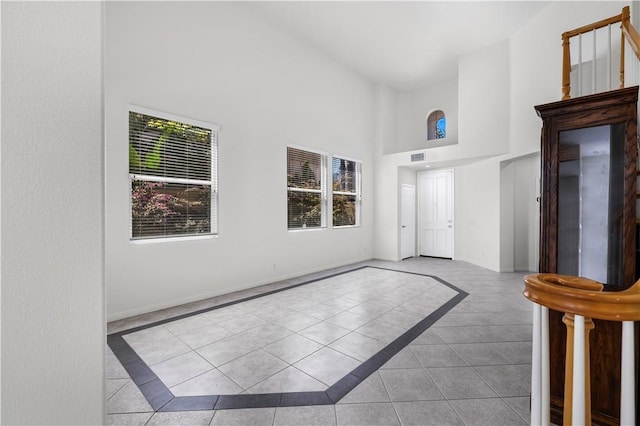 tiled entrance foyer featuring visible vents and a high ceiling