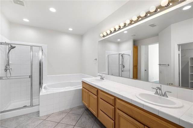 bathroom with tile patterned floors, visible vents, a stall shower, and a sink