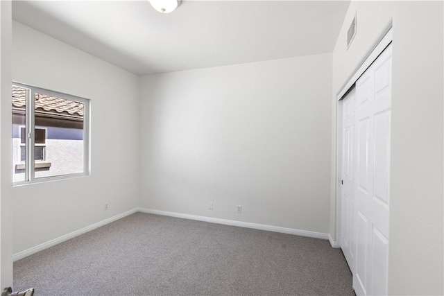 unfurnished bedroom with baseboards, visible vents, carpet floors, and a closet