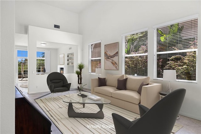 living room featuring a towering ceiling, visible vents, and light tile patterned floors