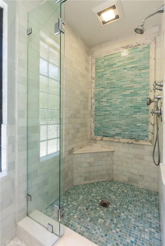 bathroom with a shower stall, visible vents, and tile walls