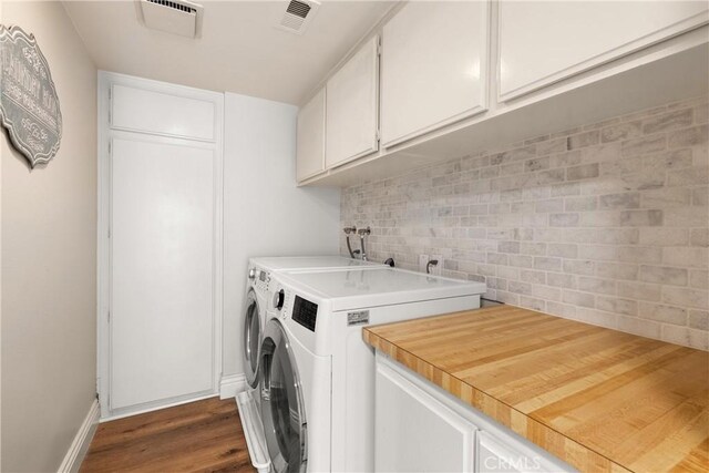 laundry area with dark wood finished floors, baseboards, visible vents, cabinet space, and washer and dryer