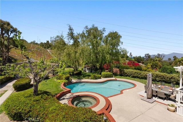 pool with a patio and an in ground hot tub
