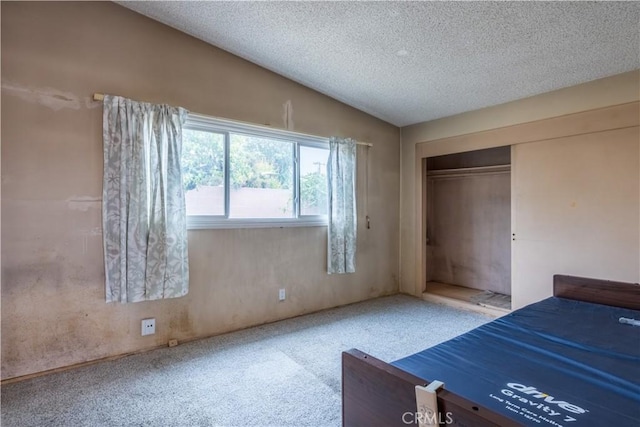 unfurnished bedroom with a closet, carpet flooring, a textured ceiling, and vaulted ceiling