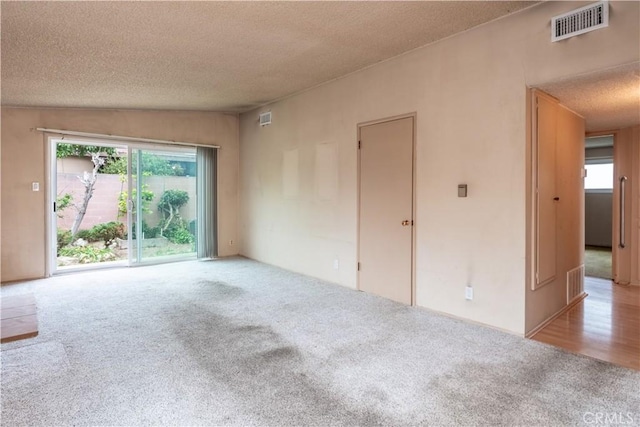 unfurnished room featuring carpet flooring, a textured ceiling, and visible vents