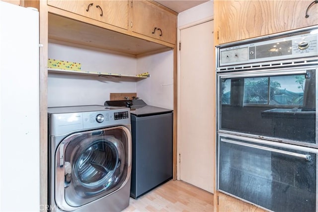 washroom featuring light wood-type flooring, cabinet space, and washer and clothes dryer