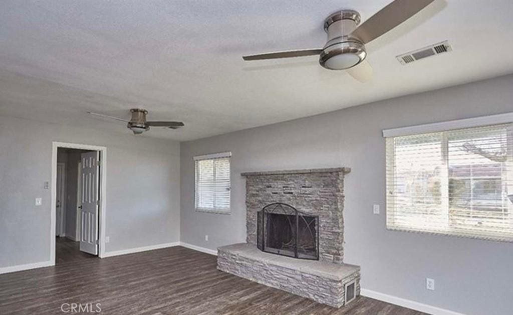 9289 Hickory Ave, Hesperia, CA 92345 - unfurnished living room with baseboards, a stone fireplace, a ceiling fan, visible vents, and wood finished floors