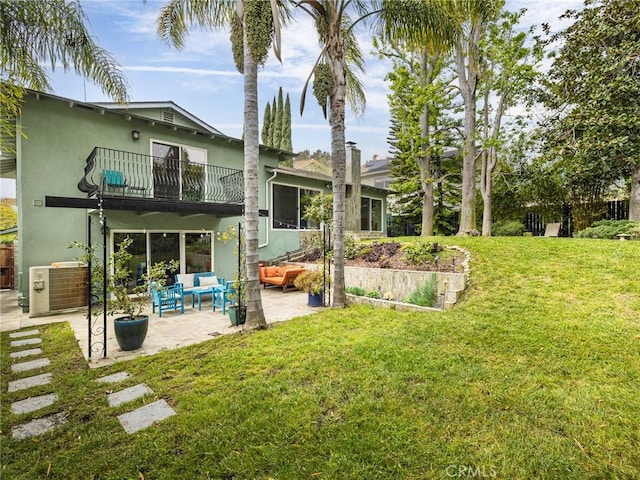 rear view of house with a balcony, outdoor lounge area, a patio area, central AC, and a lawn