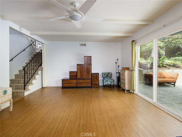 unfurnished room featuring visible vents, ceiling fan, beam ceiling, wood finished floors, and stairs